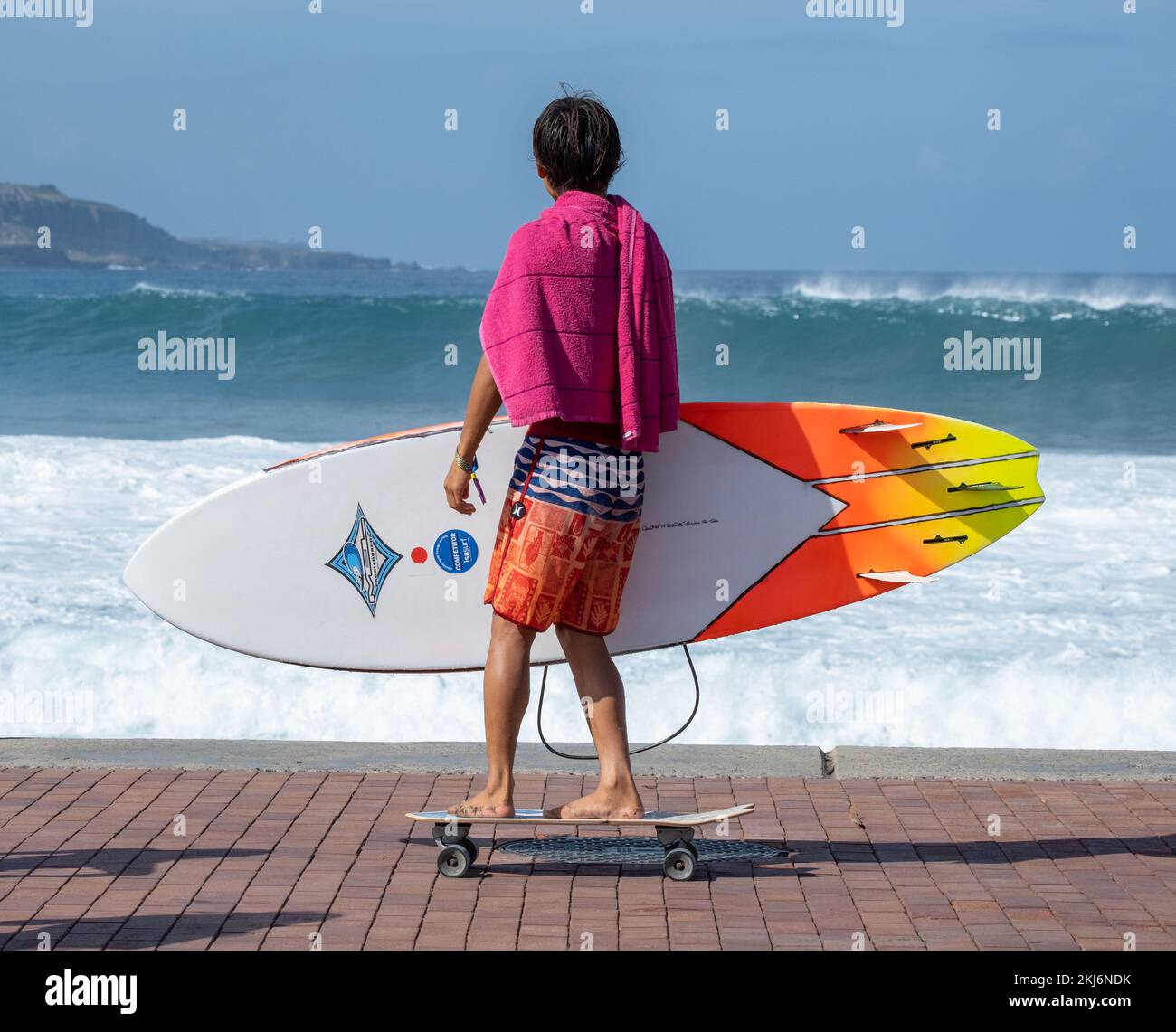 Surfista su skateboard con grandi onde sullo sfondo. Foto Stock