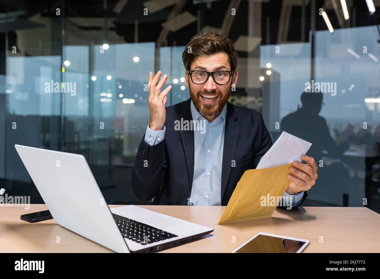 Ritratto di investitore felice uomo d'affari maturo in ufficio, l'uomo che guarda la macchina fotografica e scioccato felice e sorridente, capo busta di apertura con una buona notifica di notizie. Foto Stock