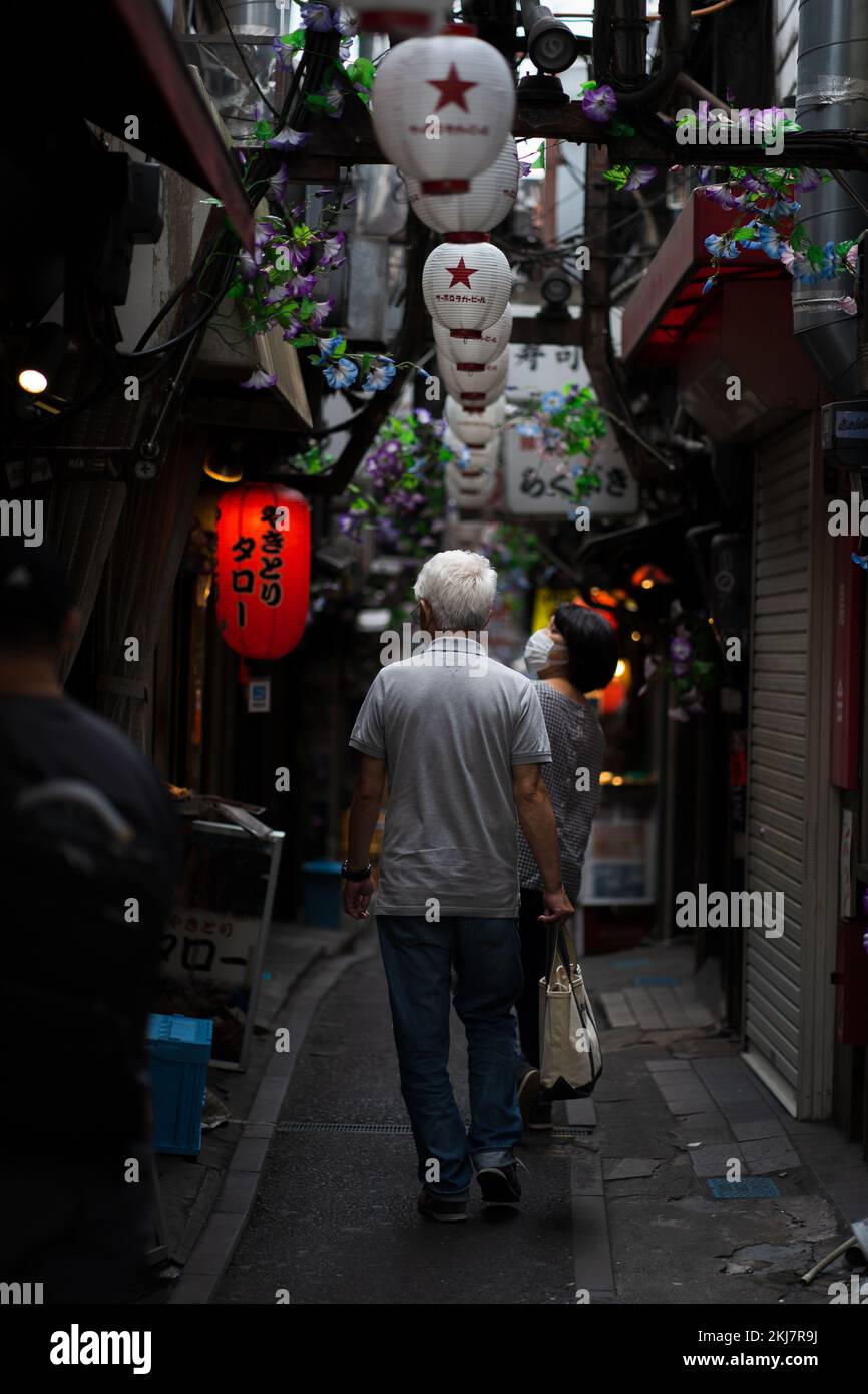 Un uomo anziano che cammina sotto lampade di carta a Omoide Yokocho a Tokyo, Giappone Foto Stock