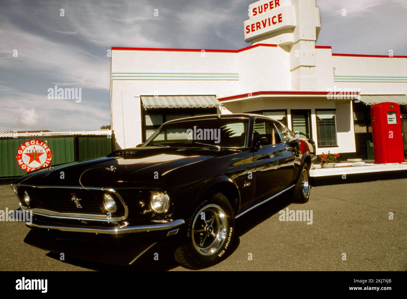 Fotografia vintage di una Ford Mustang Fastback del 1969 presso una stazione di servizio Texaco Foto Stock