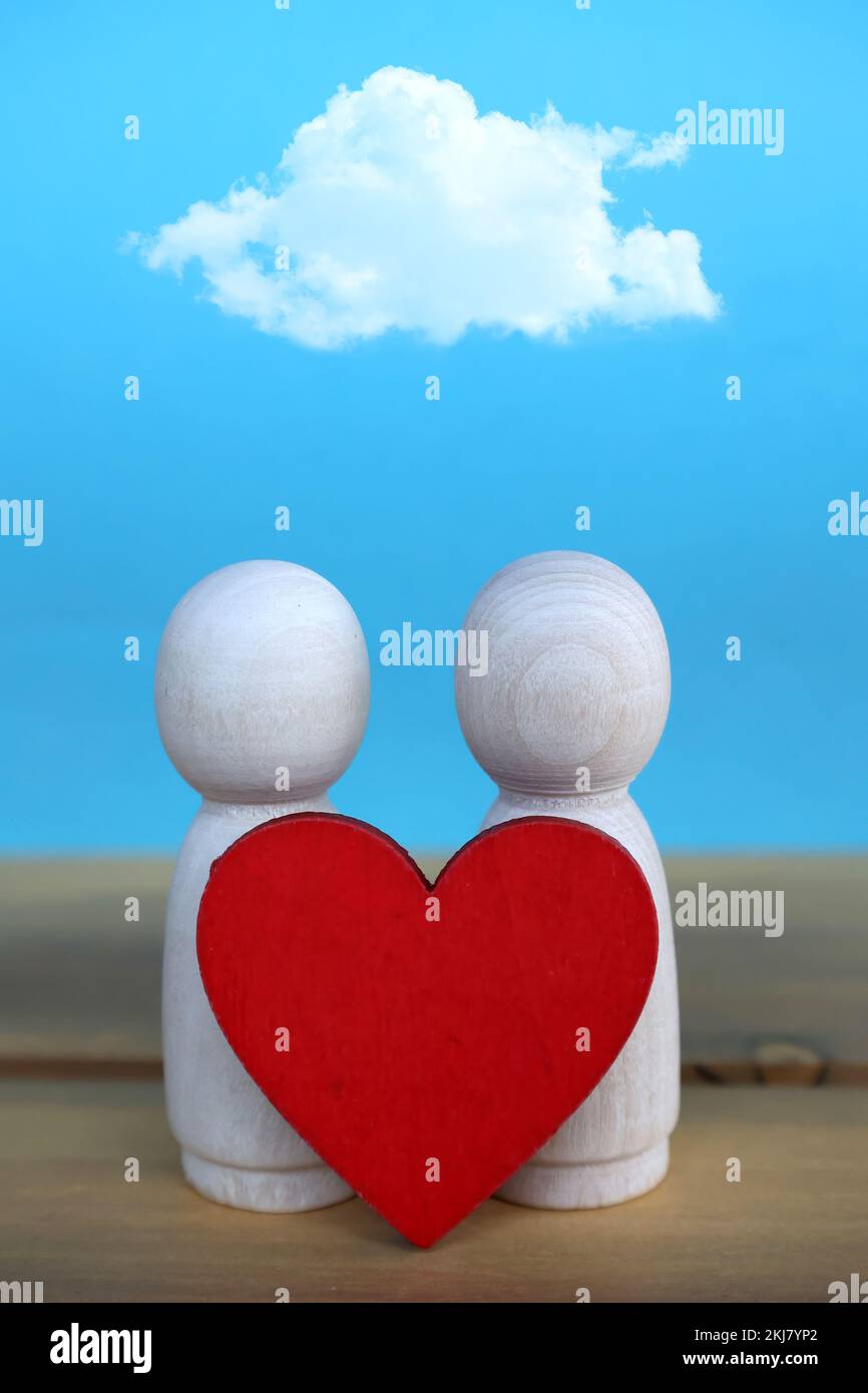 due figure in legno con cuore rosso e una nuvola sopra di esse Foto Stock