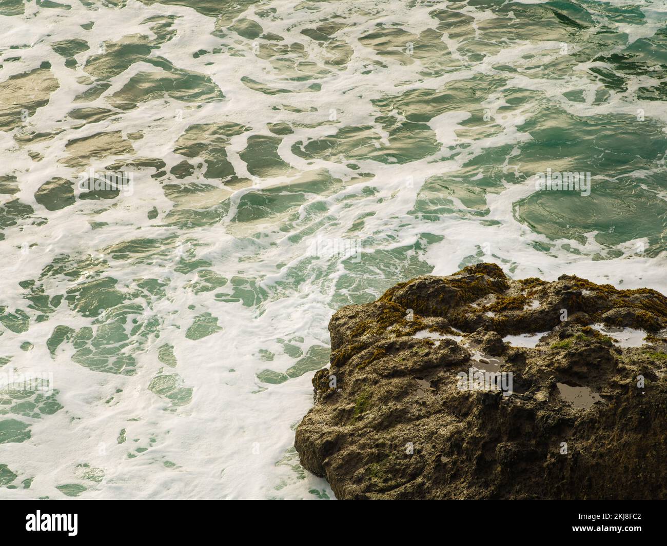 Onde bianche e schiumose si schiantano contro un grande masso nell'oceano. Tempesta, elemento. La bellezza e la grandezza della natura incontaminata. Deserto posto. Non ci sono p Foto Stock