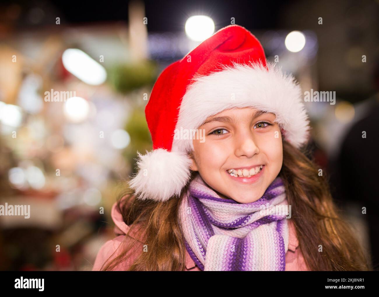 Ritratto di ragazza felice adolescente in cappello di babbo natale al mercato di strada Foto Stock