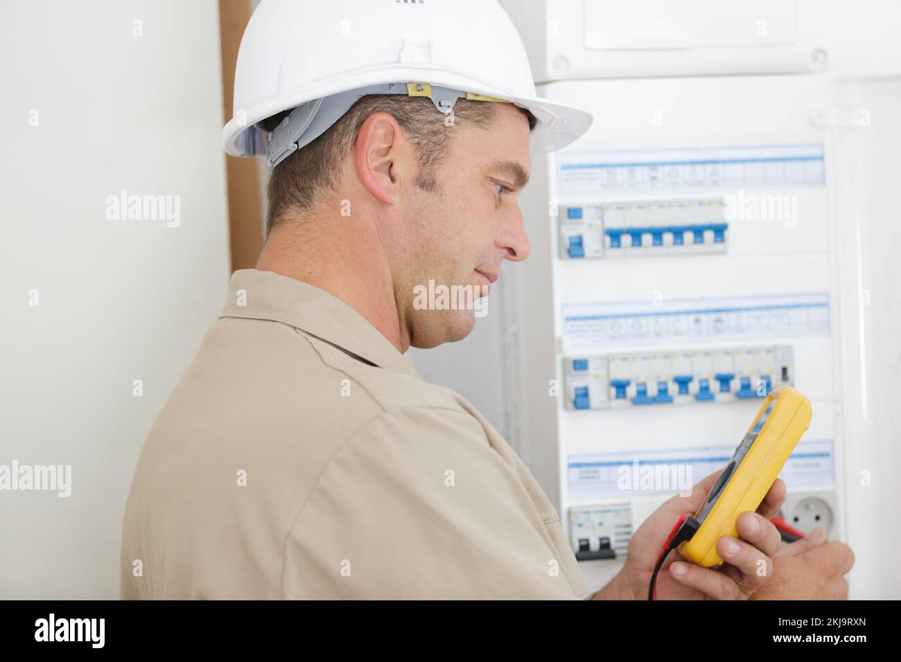 l'elettricista prova l'armadio dell'interruttore automatico con un multimetro Foto Stock