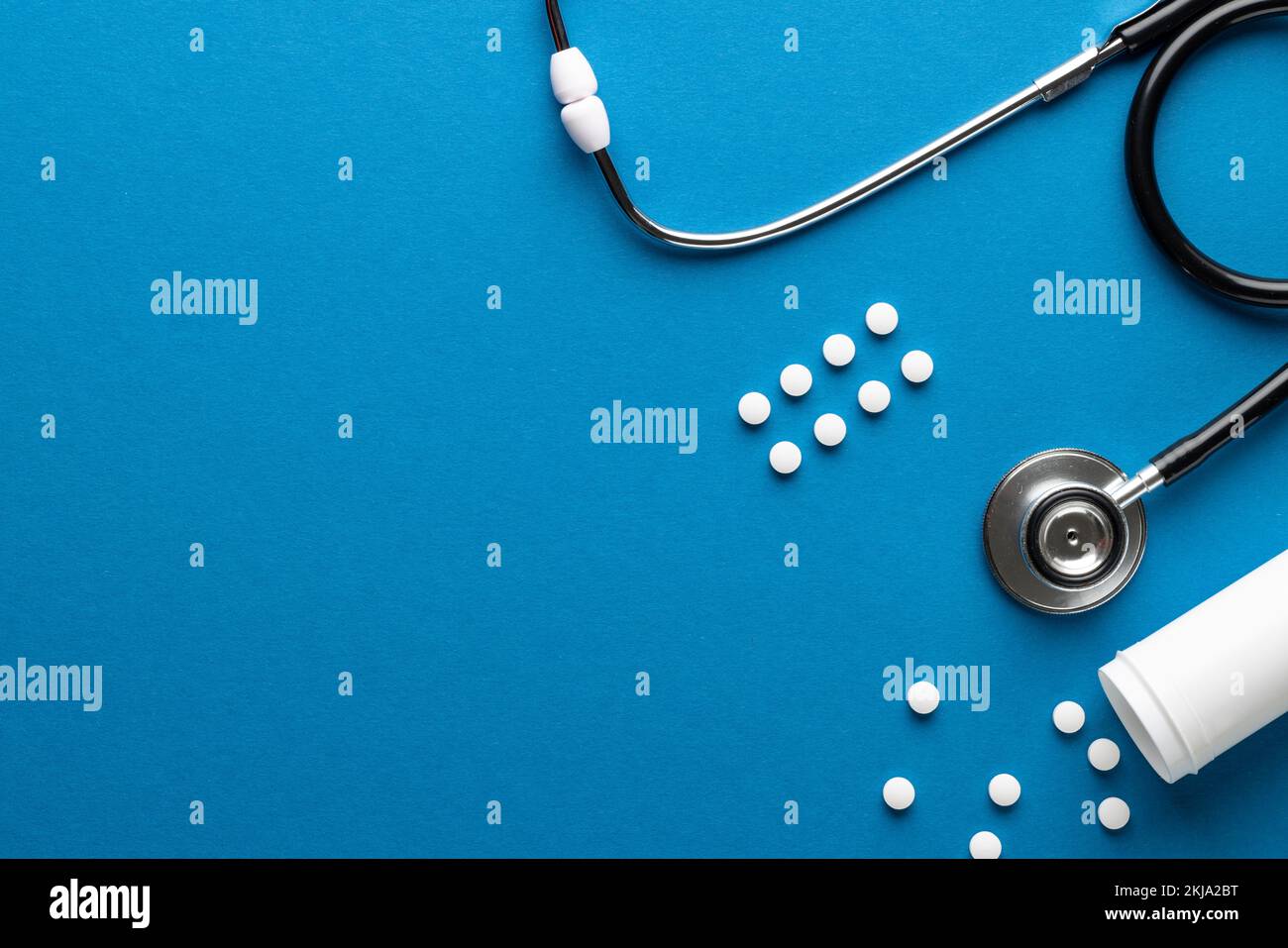 Composizione dello stetoscopio con pillole su sfondo blu con spazio di copia Foto Stock
