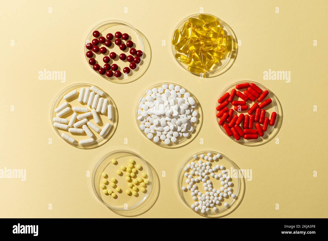 Composizione di una varietà di pillole in piatti di vetro su sfondo giallo con spazio di copia Foto Stock