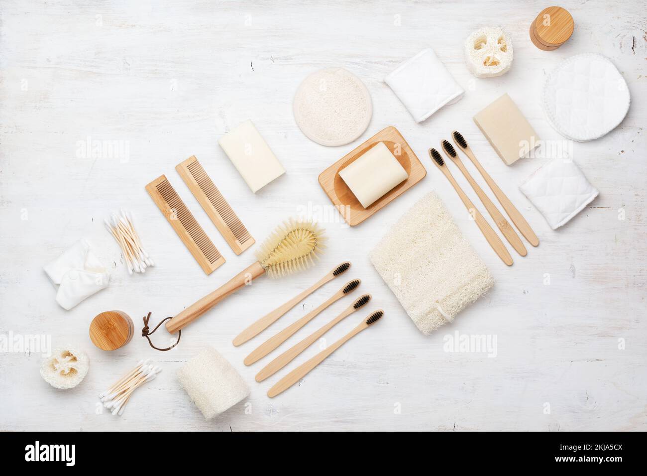 Eco concetto vivente, Creative flatlay naturale con accessori biodegradabili. Gli spazzolini da denti di bambù, sapone artigianale shampoo bar, batuffoli di cotone pastiglie, prodotti di igiene la luffa su bianco, vista dall'alto Foto Stock