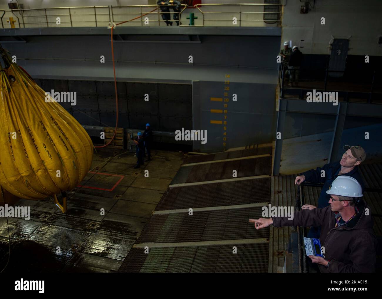 221122-N-VO895-1020 NORFOLK, VIRGINIA (22 novembre 2022) il compagno capo di Boatswain Jonathan Fries, assegnato alla nave d’assalto anfibio di classe Wasp USS Bataan (LHD 5) Deck Department, e Scott McDonald, coordinatore dei test di peso per il Mid Atlantic Regional Maintenance Center, testano le attrezzature vitali per i ponti pozzi nel ponte pozzi della nave, il 22 novembre 2022. Il test di carico valuta la forza dello scafo e il supporto del pozzo degli occhi imbottiti ad aria (LCAC) dell'imbarcazione di atterraggio di Bataan. (STATI UNITI Foto Navy di Mass Communication Specialist 2nd Class Danilo Reynoso) Foto Stock