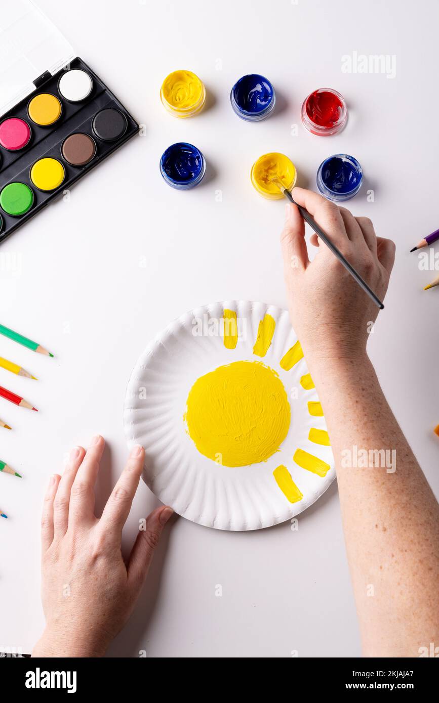 Verticale di pittura a mano con giallo su lastra di carta e materiali artistici sul piano del tavolo, spazio copia Foto Stock