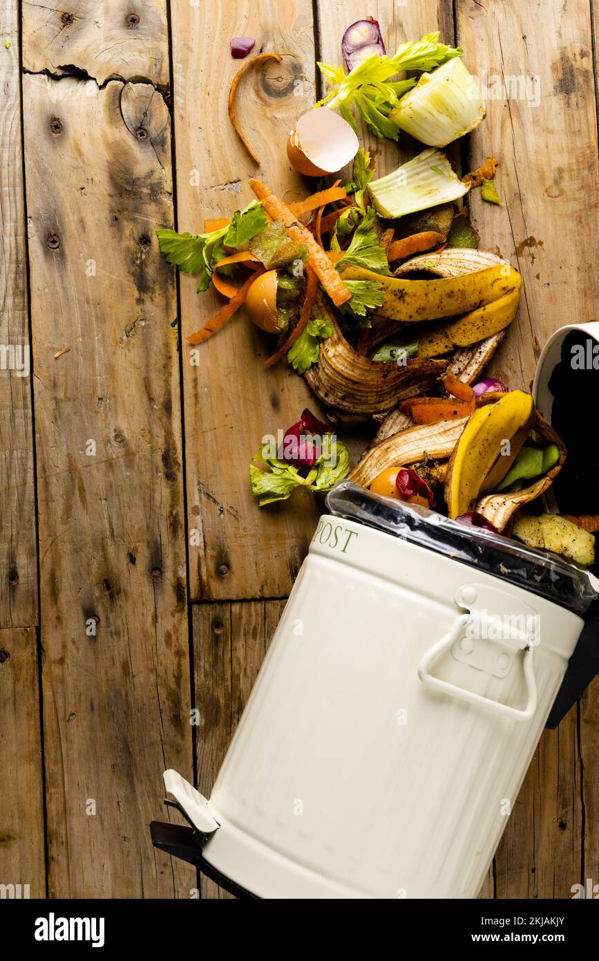 Immagine verticale dei rifiuti organici di frutta e verdura che si versano dal contenitore per compostaggio della cucina Foto Stock