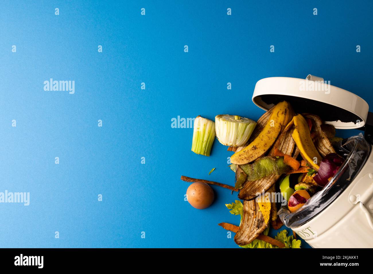 Scarti di frutta e verdura biologici che si versano dal contenitore aperto di compostaggio della cucina Foto Stock