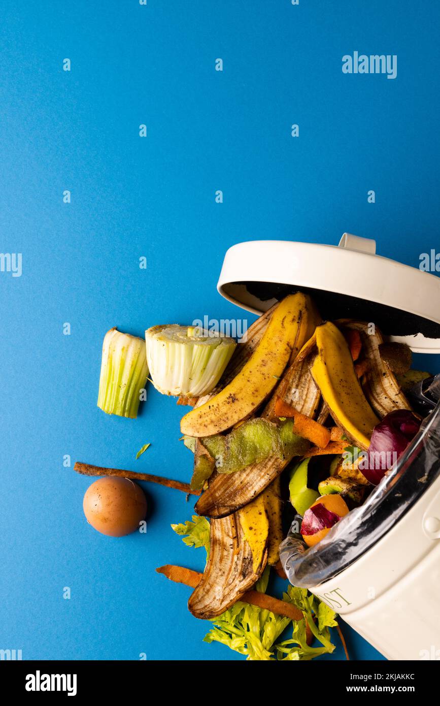 Immagine verticale dei rifiuti organici di frutta e verdura che si versano dal contenitore per compostaggio della cucina Foto Stock