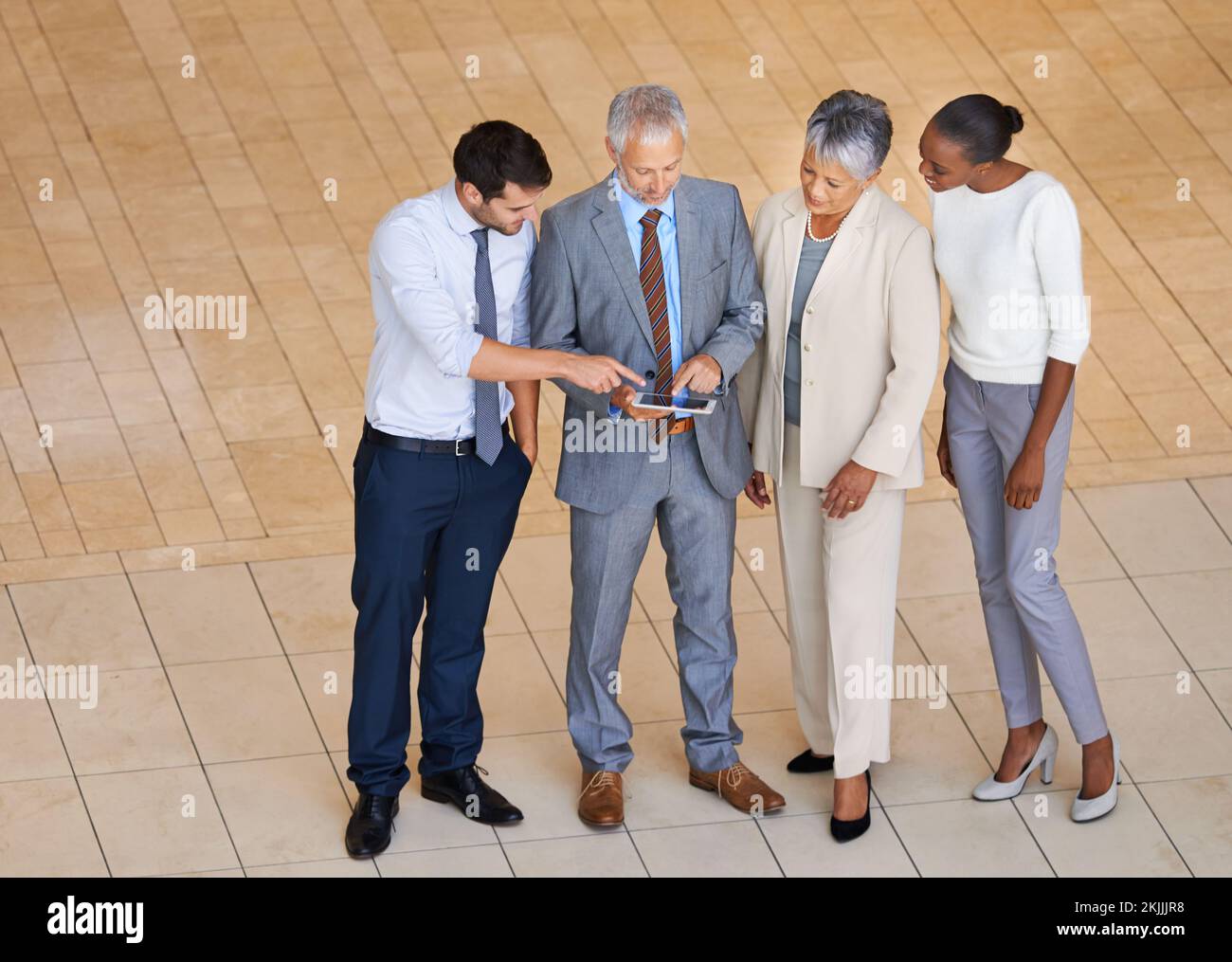 Allenando il loro piano di gioco. Vista ad angolo alto di un gruppo di uomini d'affari in piedi con un tablet digitale e in discussione sul lavoro. Foto Stock