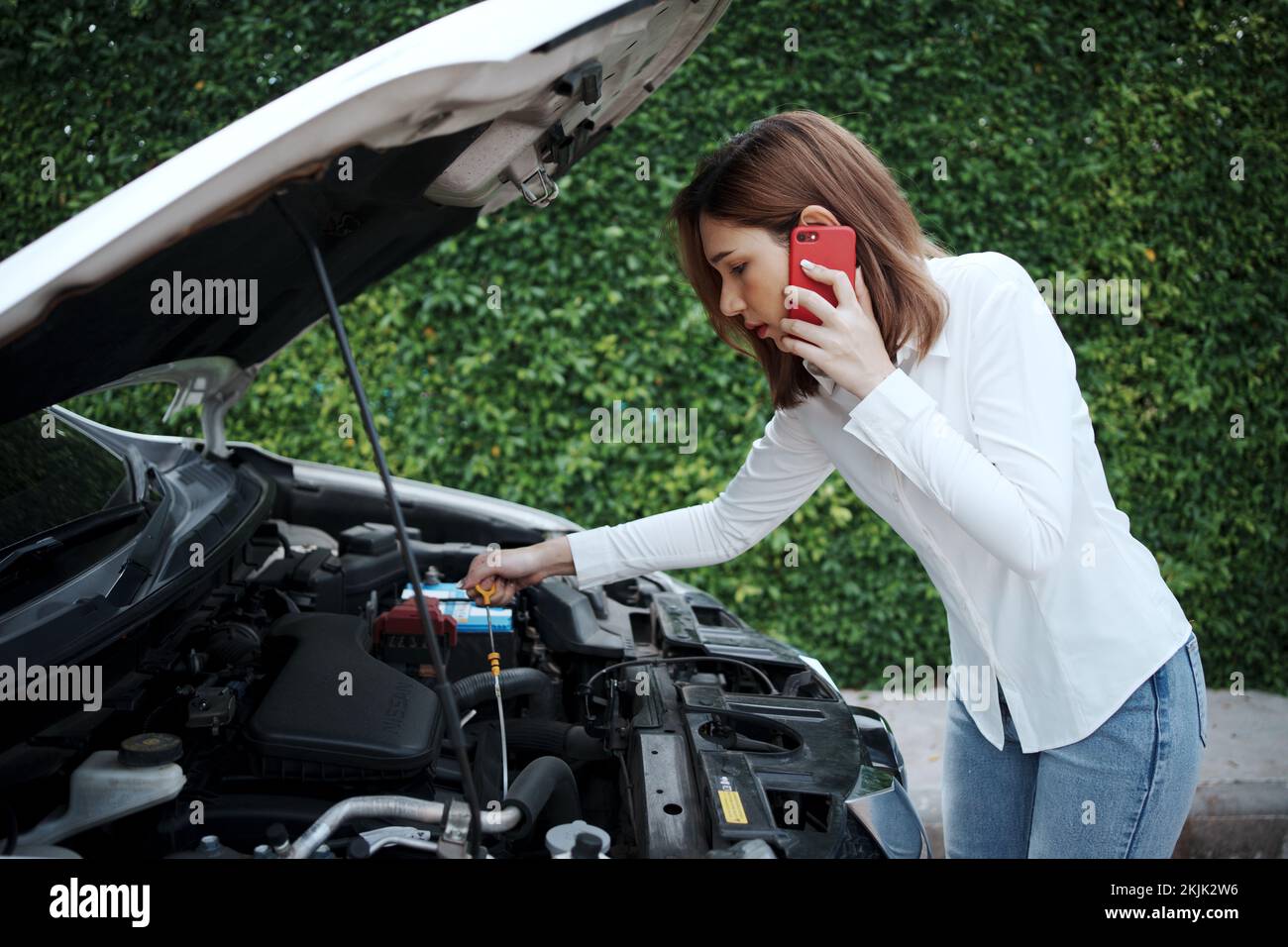 Donna che utilizza il telefono cellulare per richiedere assistenza dopo un guasto dell'auto sulla strada. Foto Stock
