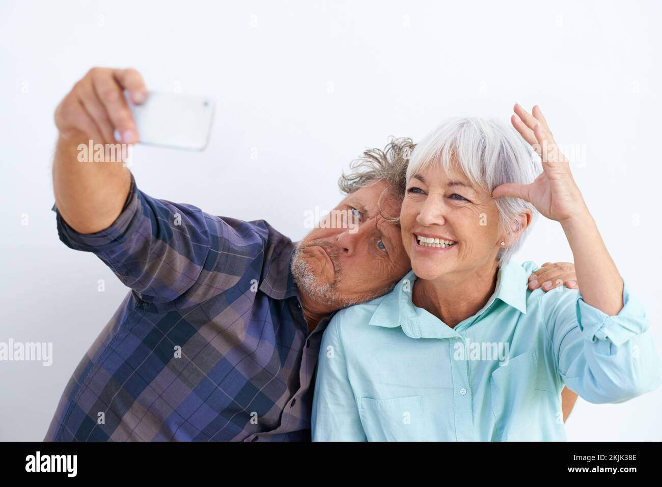 Crescere è facoltativo. una coppia anziana affettuosa che gioca intorno mentre scatta le foto di se stessi con un telefono cellulare. Foto Stock