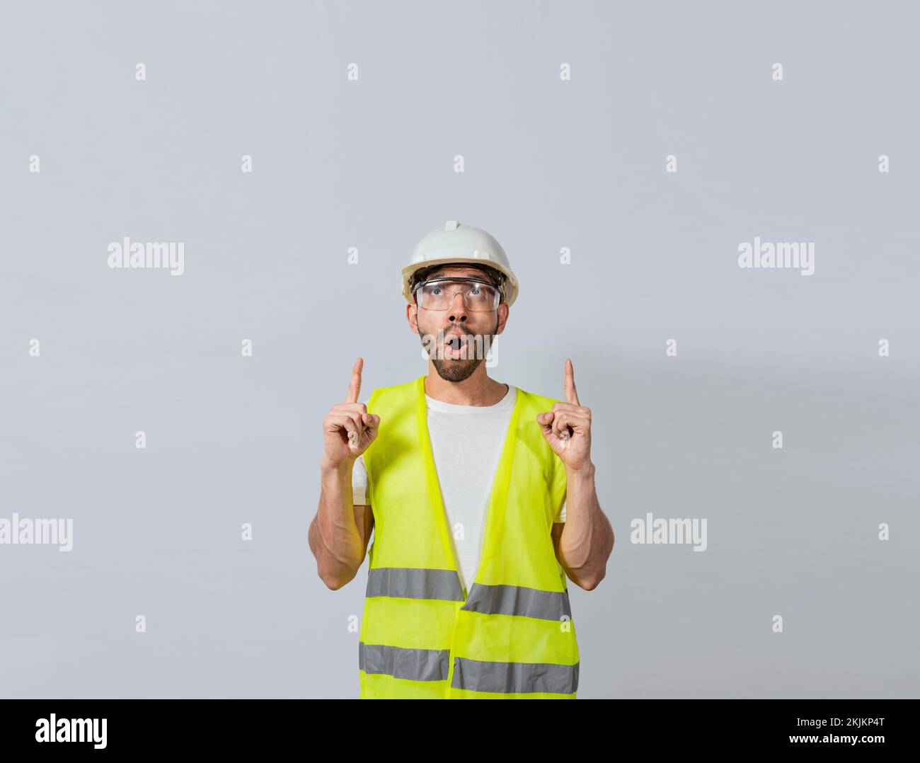 Stupito giovane architetto che indica in su, stupito ingegnere che indica un annuncio. Concetto di ingegnere con il volto stupito che punta a Blank spa Foto Stock