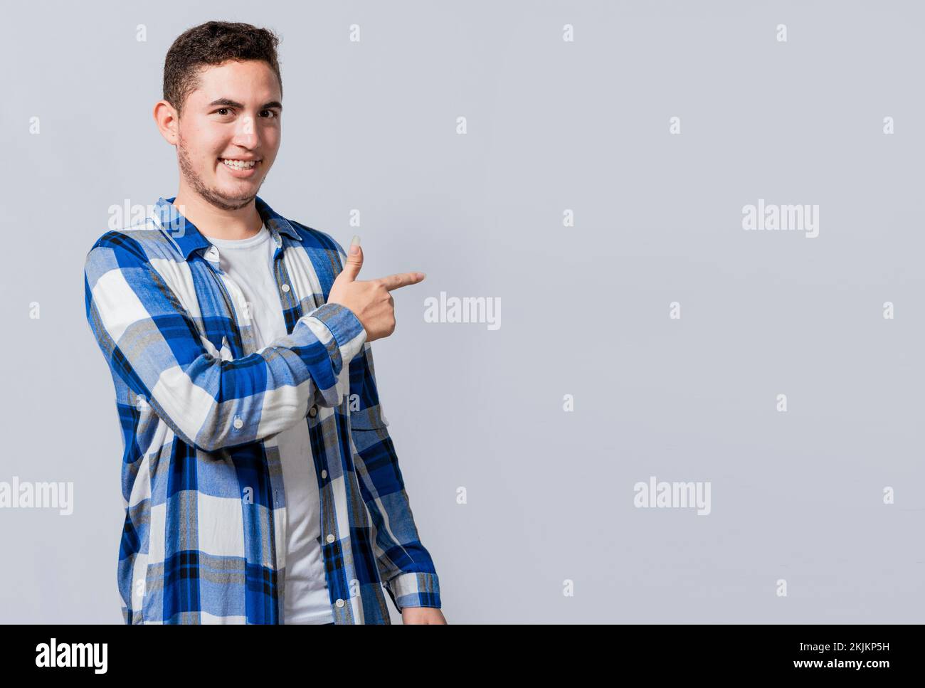 Un bell'uomo sorridente che consiglia qualcosa con le dita. Bel ragazzo caucasico puntando il dito in uno spazio vuoto, sorridendo adolescente puntando f Foto Stock
