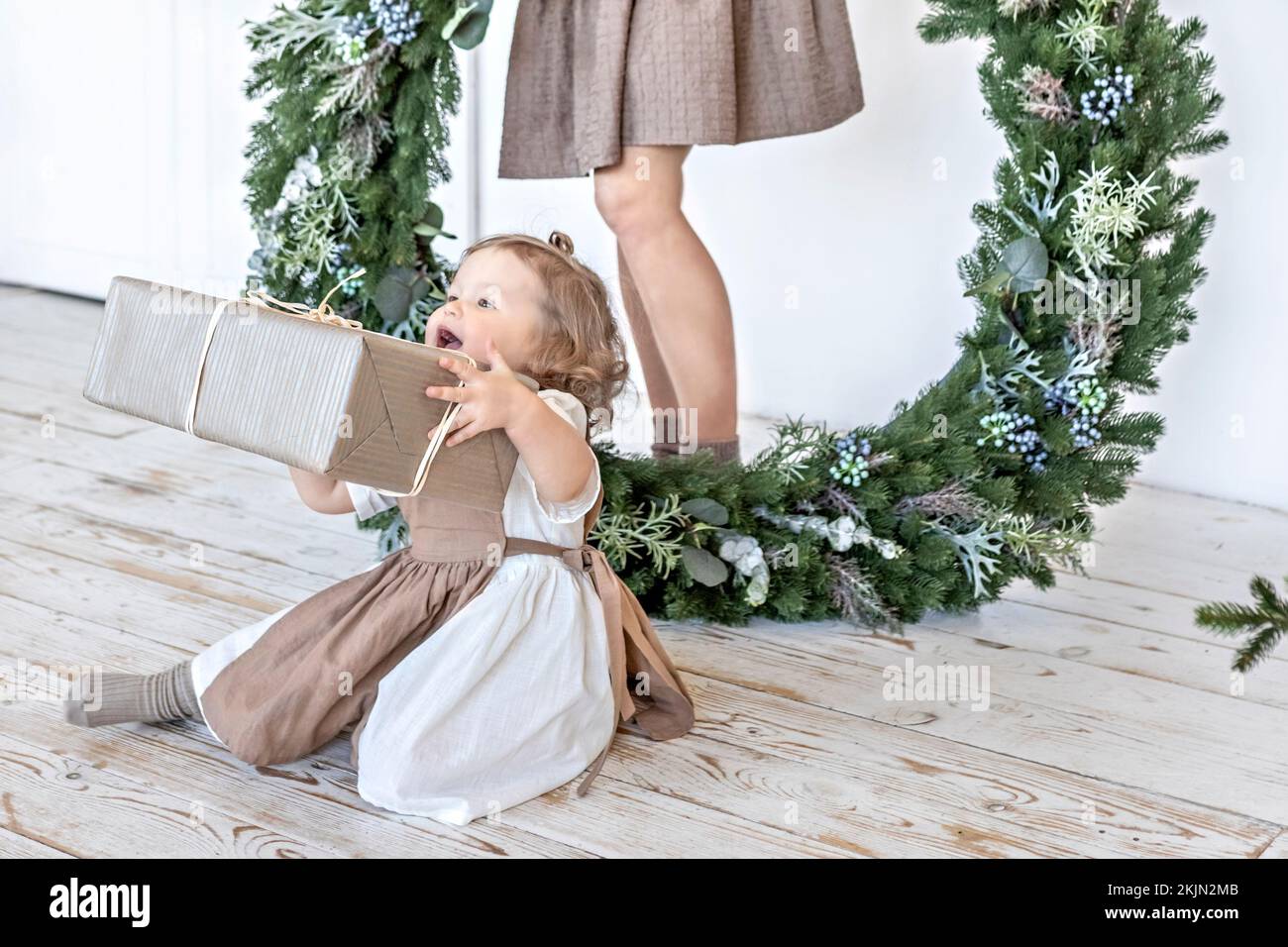 Una giovane donna con i capelli biondi e una figlia piccola con una corona di Natale. Concetto di Capodanno, decorazioni di Natale. Foto Stock