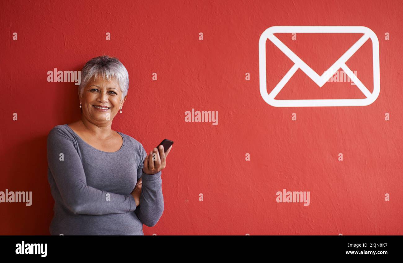 Hai ricevuto la posta. una donna matura che tiene in mano un telefono cellulare con un'icona di messaggio accanto a lei sulla parete. Foto Stock