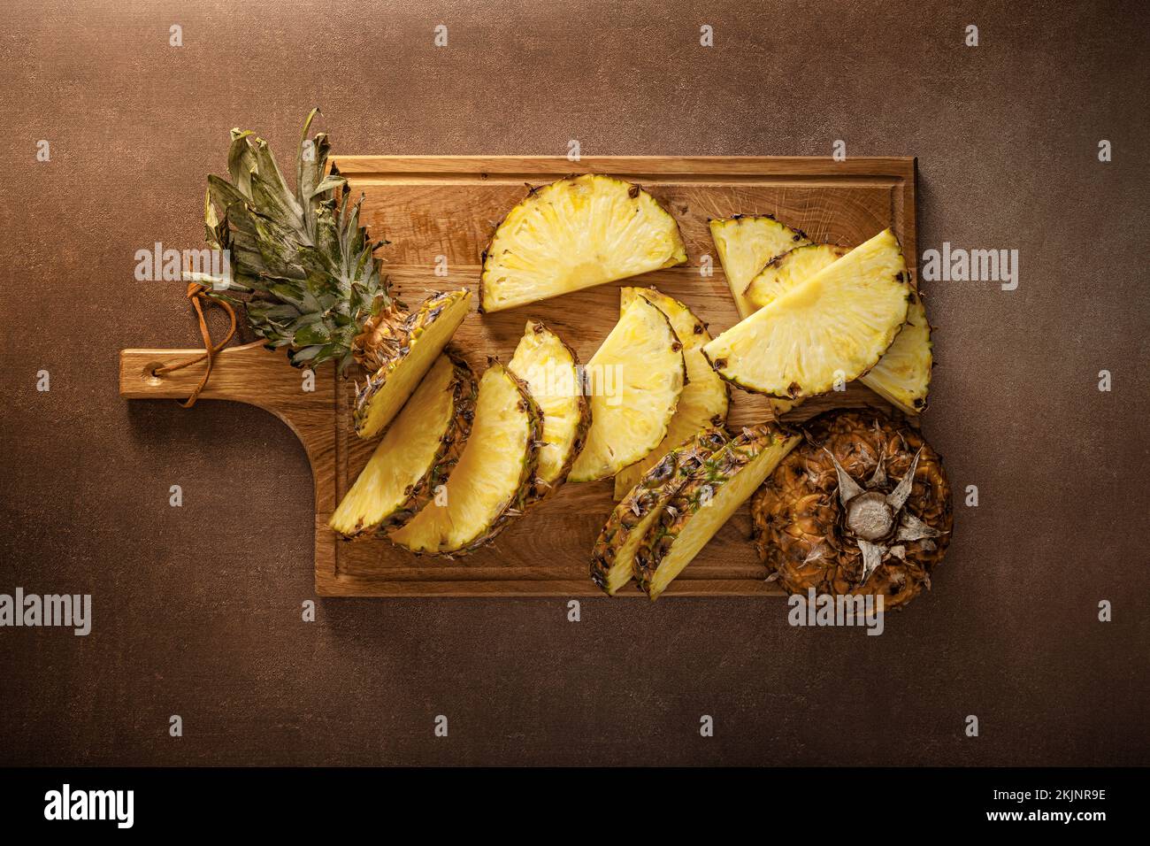 Ananas. Ananas a fette e intero su fondo marrone, vew superiore Foto Stock