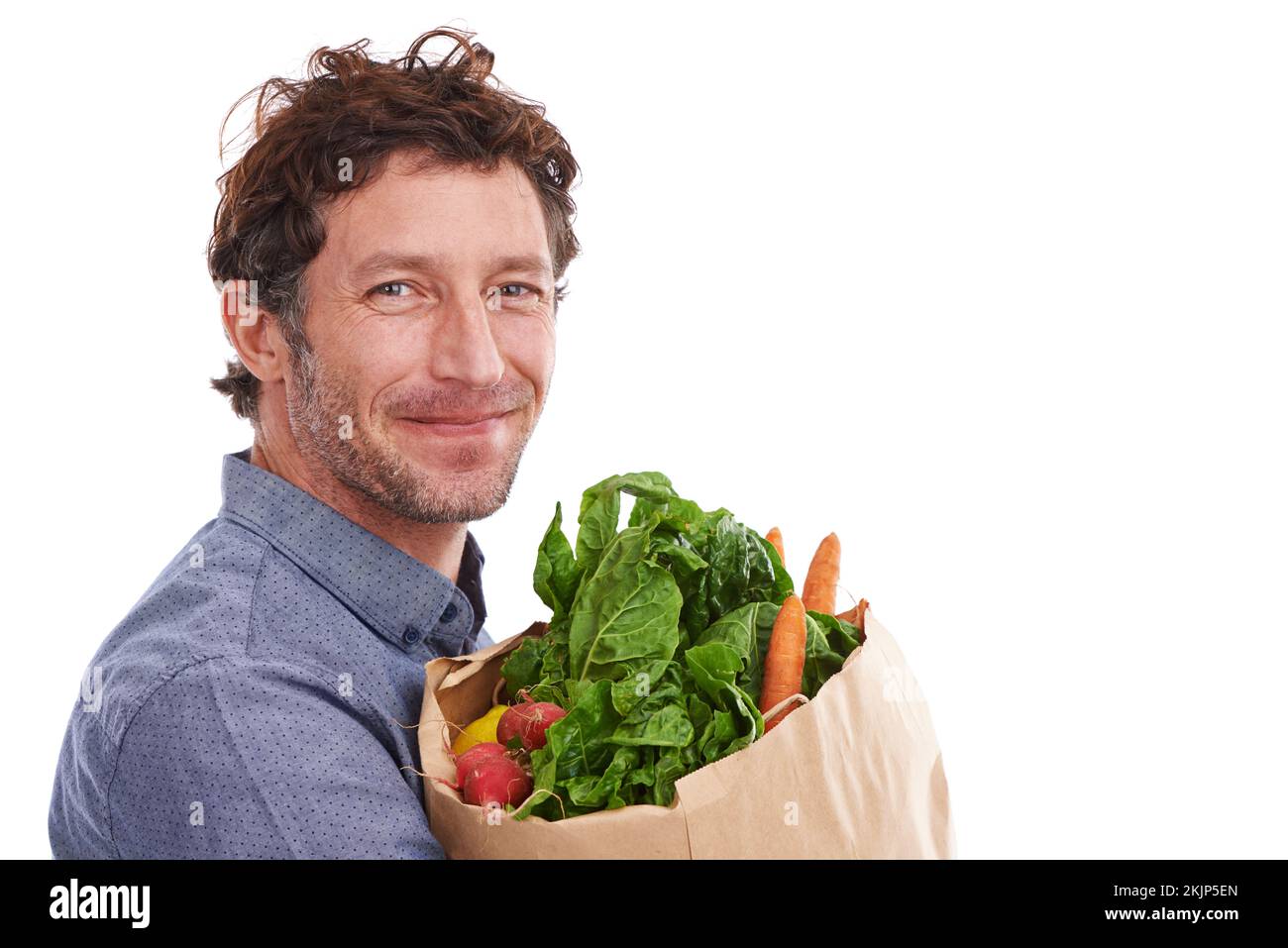 A mia moglie piace quando faccio lo shopping. Studio shot di un bel giovane uomo in possesso di una shopping bag piena di verdure fresche. Foto Stock