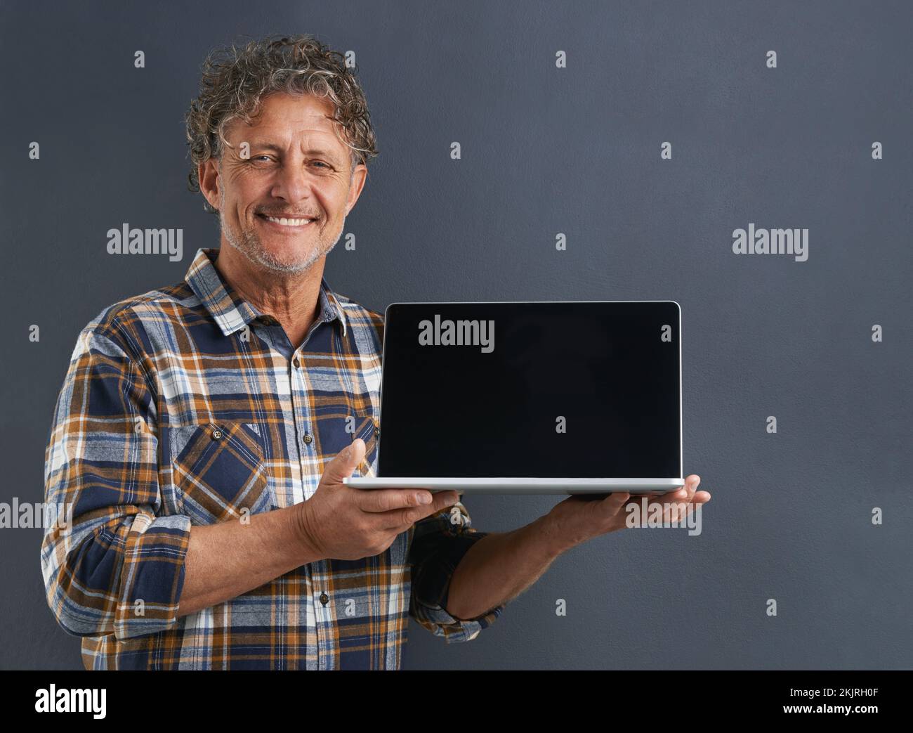 Navigazione nel sito Web. Un ritratto di un maturo che mostra un notebook con uno schermo vuoto. Foto Stock