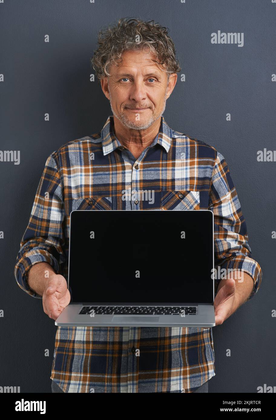 La tua pagina web va qui. Un ritratto di un maturo che mostra un notebook con uno schermo vuoto. Foto Stock