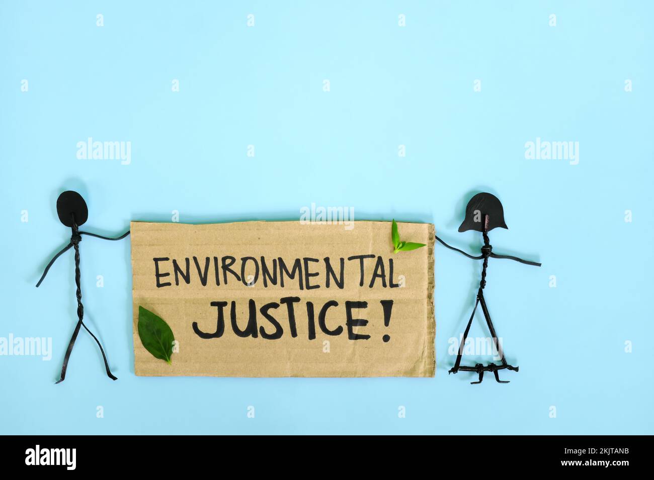Giustizia ambientale, giustizia ecologica e climatica. Le persone attaccano le figure che protestano mentre tengono un cartellone di cartone Foto Stock