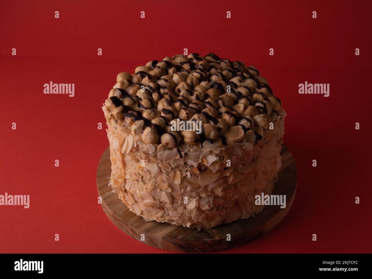 foto torta di noce intera su un asse di legno su uno sfondo rosso Foto Stock