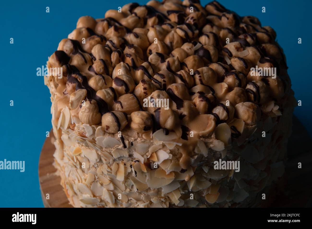 Foto ravvicinata di una torta di noce intera su un asse di legno su sfondo blu Foto Stock