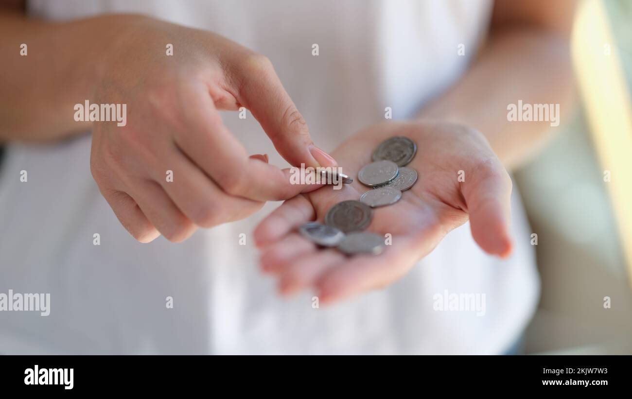 Mani femminili che tengono e contano monete d'argento Foto Stock