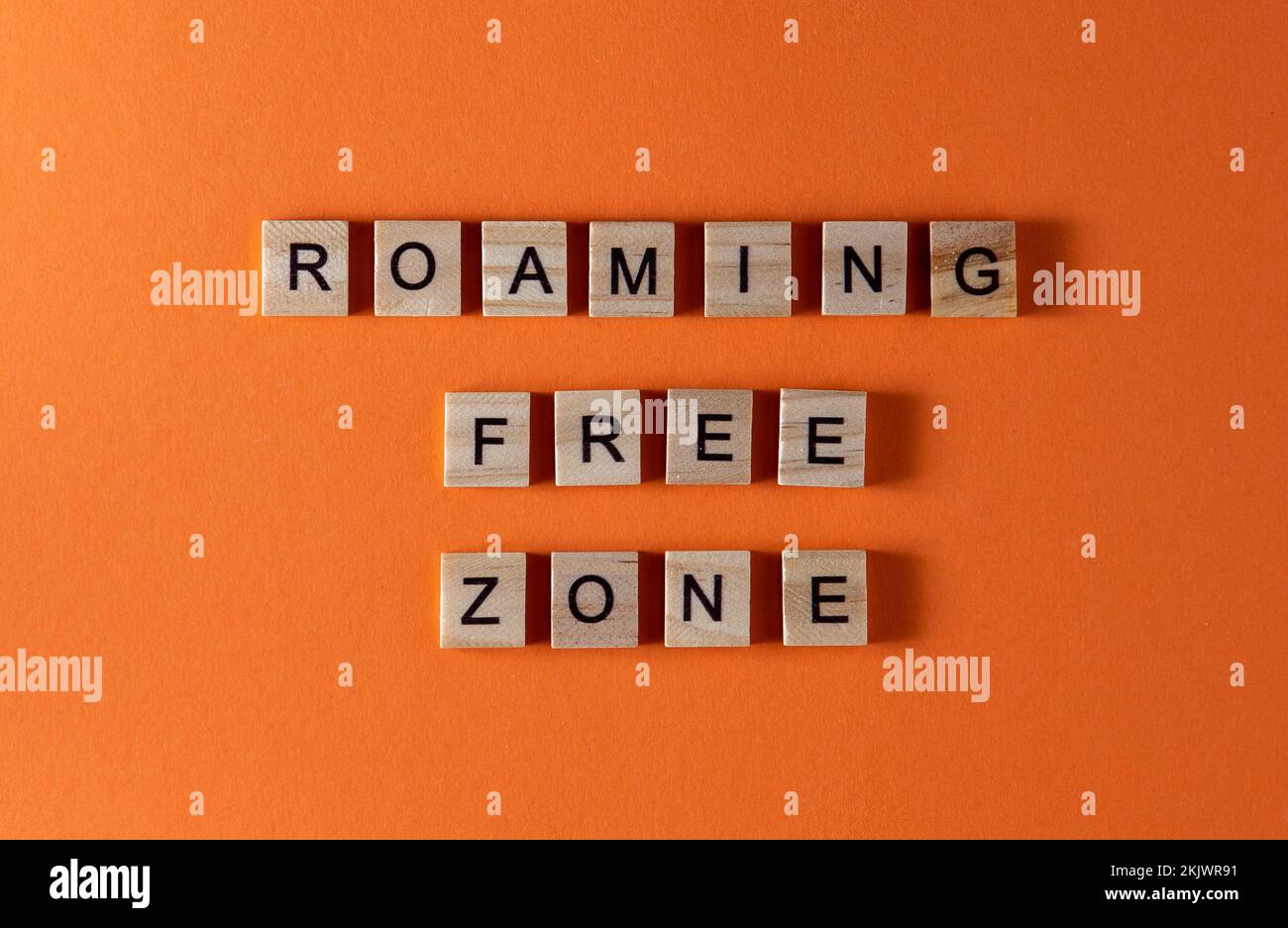 Frase in lettere di legno per la zona libera in roaming. Motivazione e slogan. Sfondo arancione. Foto Stock