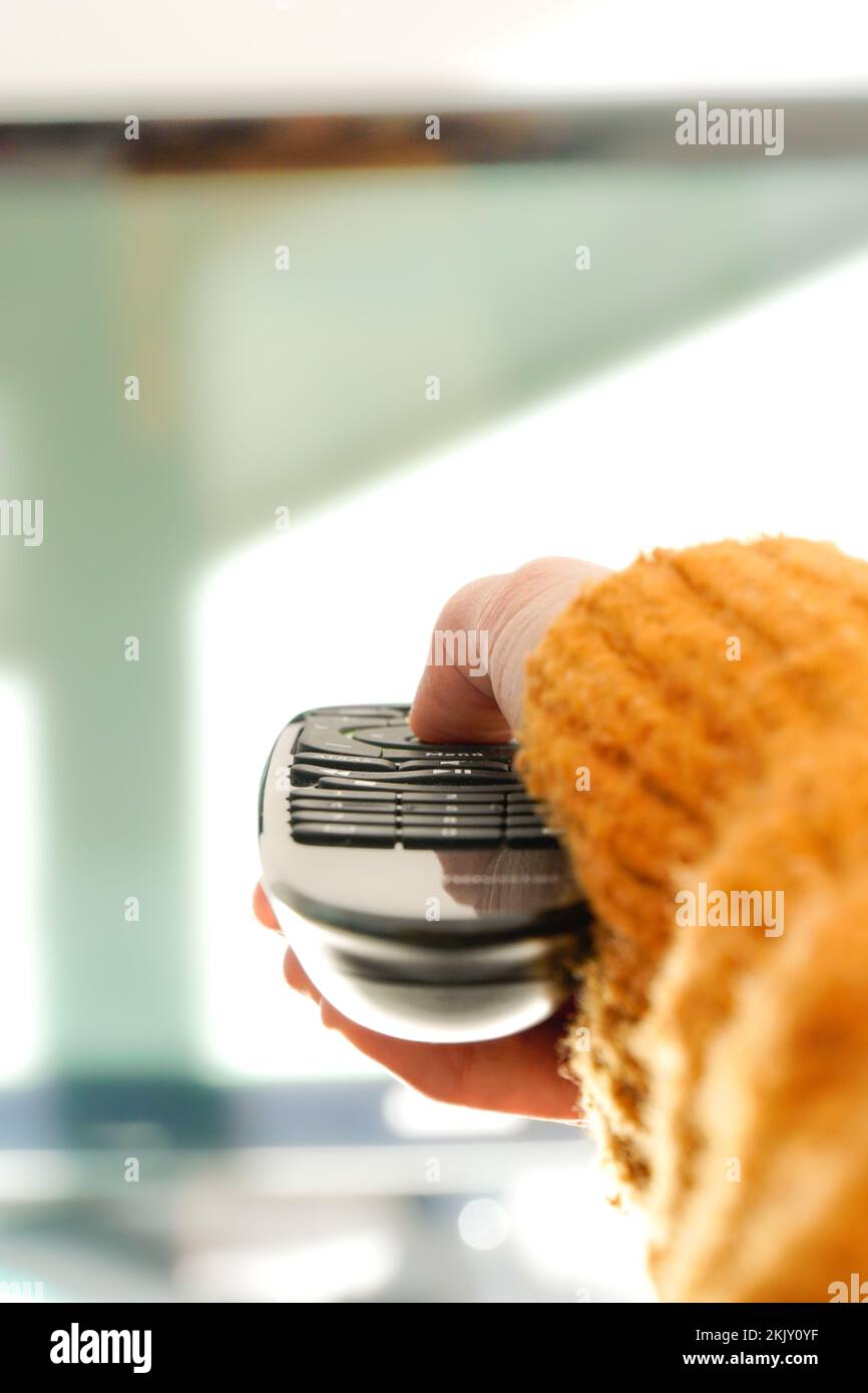 donna che cambia la mano canale con il telecomando della televisione a casa Foto Stock