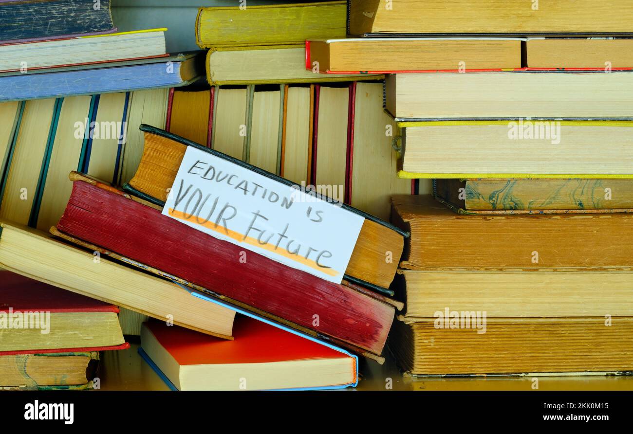 Stack di libri hardback in una biblioteca con l'istruzione è il vostro futuro sign.Learning, l'istruzione, la conoscenza, il ritorno al concetto di scuola. Foto Stock