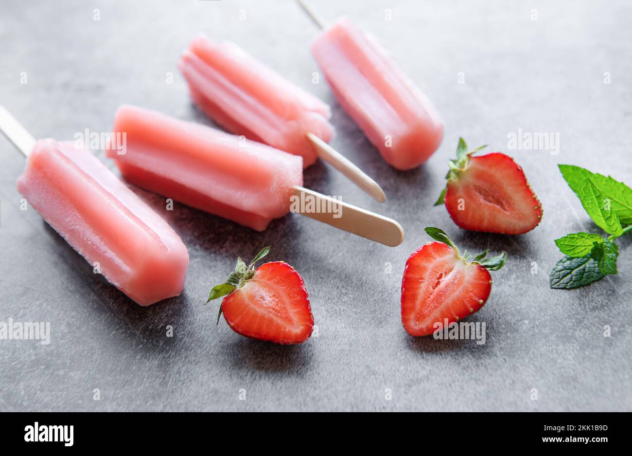 Gelato alla fragola surgelato fatto in casa e fragole fresche su sfondo di cemento. Dessert estivo Foto Stock