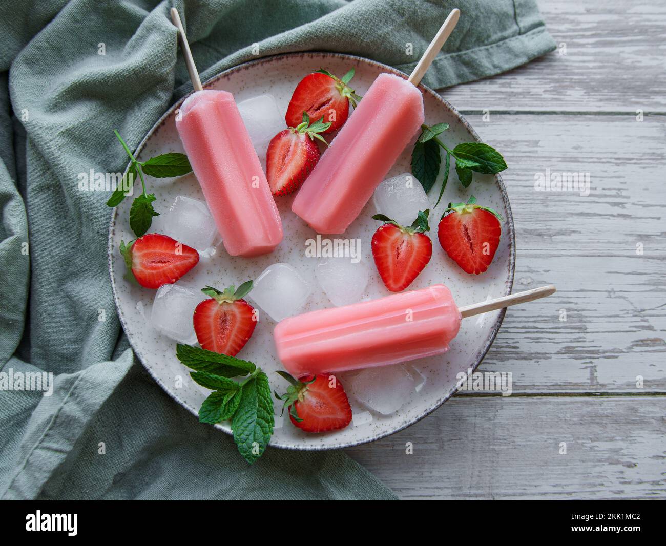 Gelato alla fragola surgelato fatto in casa e fragole fresche su sfondo di cemento. Dessert estivo Foto Stock