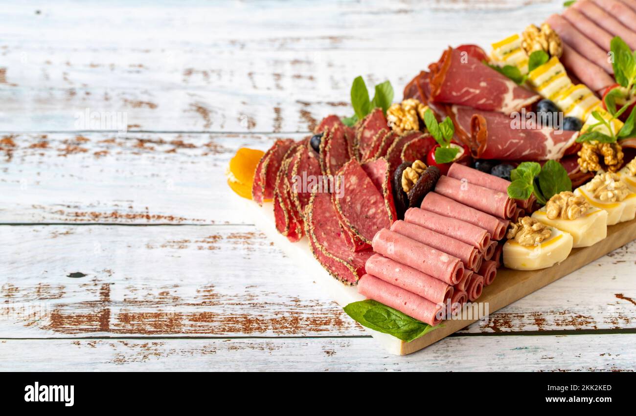 Piatto di carne affumicata fredda su pavimento in legno. Set antipasto plater in legno. Affumicato freddo con prosciutto, salame, pancetta, cotoletta di vitello. Spazio di copia Foto Stock