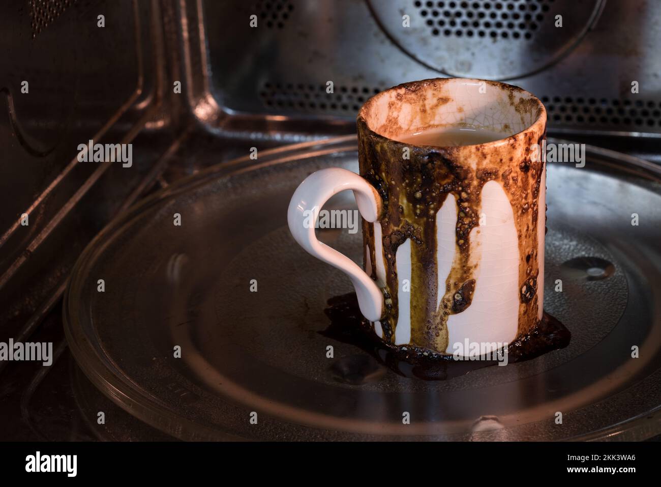 La bevanda di caffè traboccata di Spilt nel microonde che causa il mess serio ripulire come dimenticato & ha messo sull'impostazione errata che giocolano troppe cose multitasking Foto Stock