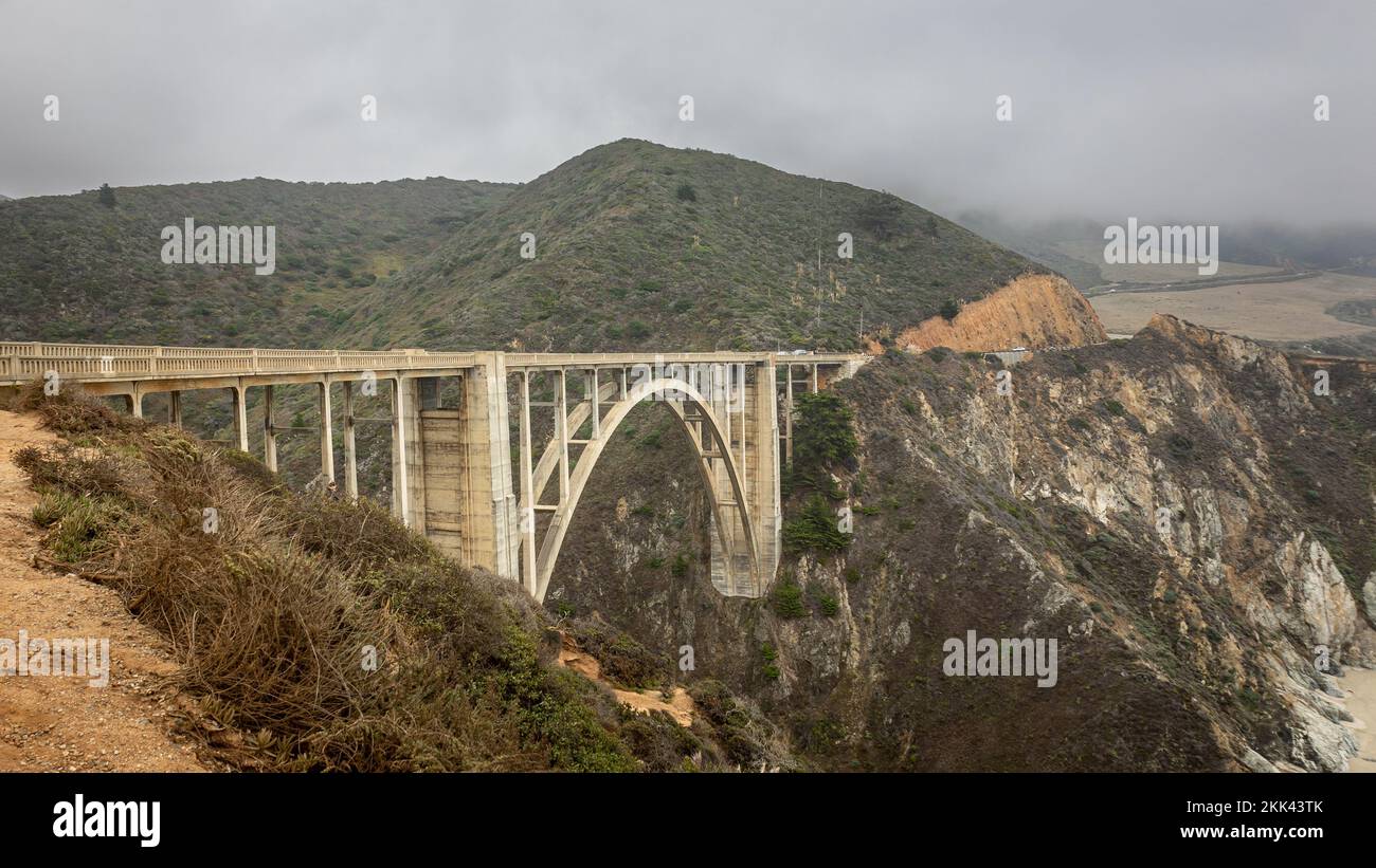 Il ponte Bixby nella zona costiera di Big sur con ripide scogliere nelle vicinanze, nello stato della California degli Stati Uniti, in una giornata di nebbia nuvolosa. Foto Stock