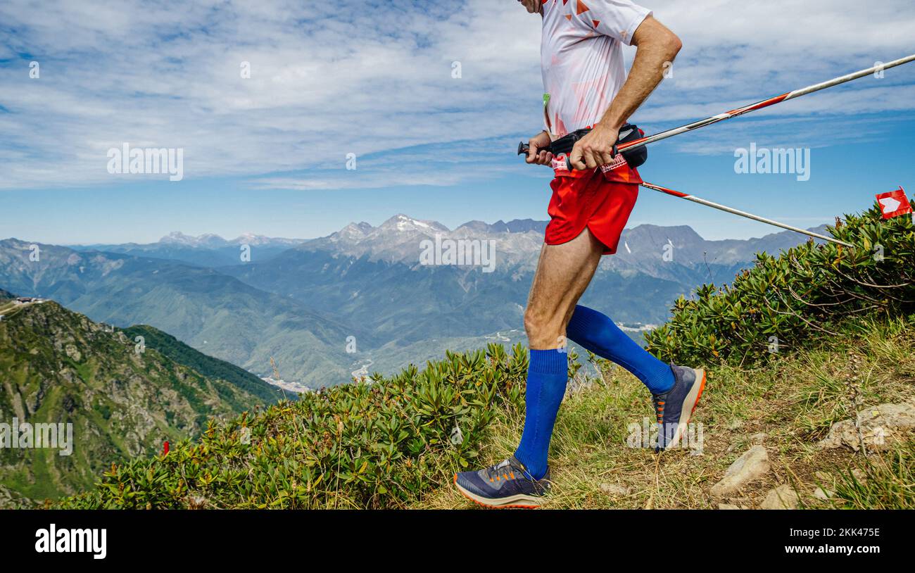 atleta maschile che corre maratona di montagna con bastoni da trekking Foto Stock