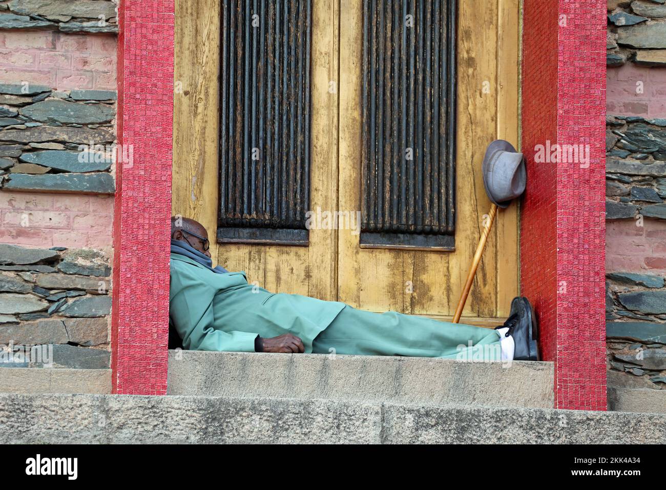 Signore anziano che dorme in una porta di una chiesa ad Asmara Foto Stock