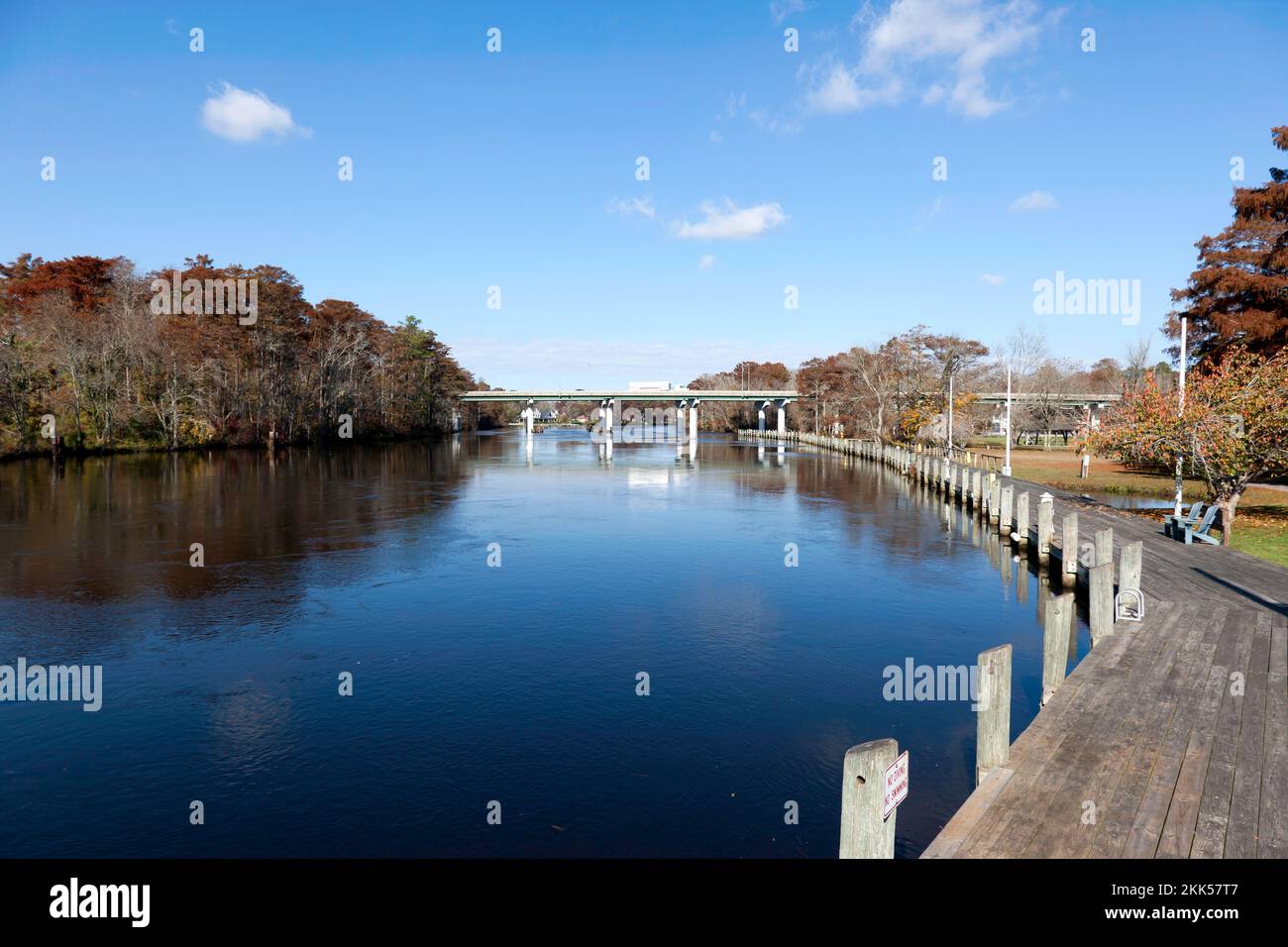 Passeggiata lungo il bordo del Cypress Park, vicino al fiume Pocomoke, Pocomoke City, con il Ponte a doppio fascio di acciaio, sullo sfondo Foto Stock