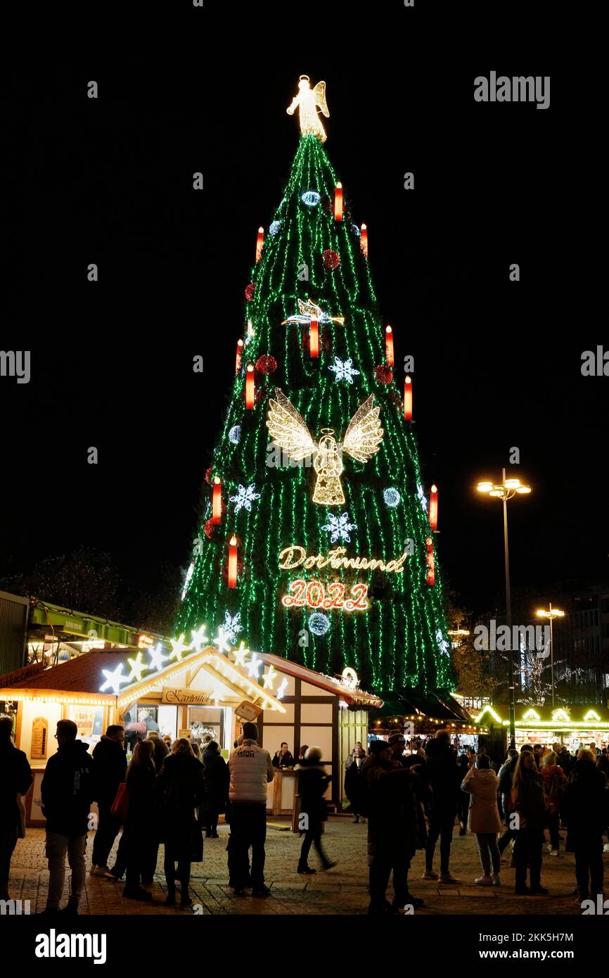 Dortmund, Germania, 22nd novembre 2022: Un angelo alto quattro metri con una tromba brilla sulla cima del più grande albero di Natale del mondo. L'albero di Natale alto 45 metri al mercato di Natale di Dortmund è composto da 1.000 alberi di abete rosso della Sauerland ed è appeso con 48.000 luci a LED. --- Dortmund, 22.11.2022: Auf der Spitze des größten Weihnachtsbaum der Welt leuchtet ein vier Meter großer Engel mit einer Posaune. Der 45 Meter hohe Weihnachtsbaum auf dem Dortmunder Weihnachtsmarkt besteht aus 1000 Rotfichten aus dem Sauerland und ist mit 48,000 LED-Lichtern behängt. Foto Stock