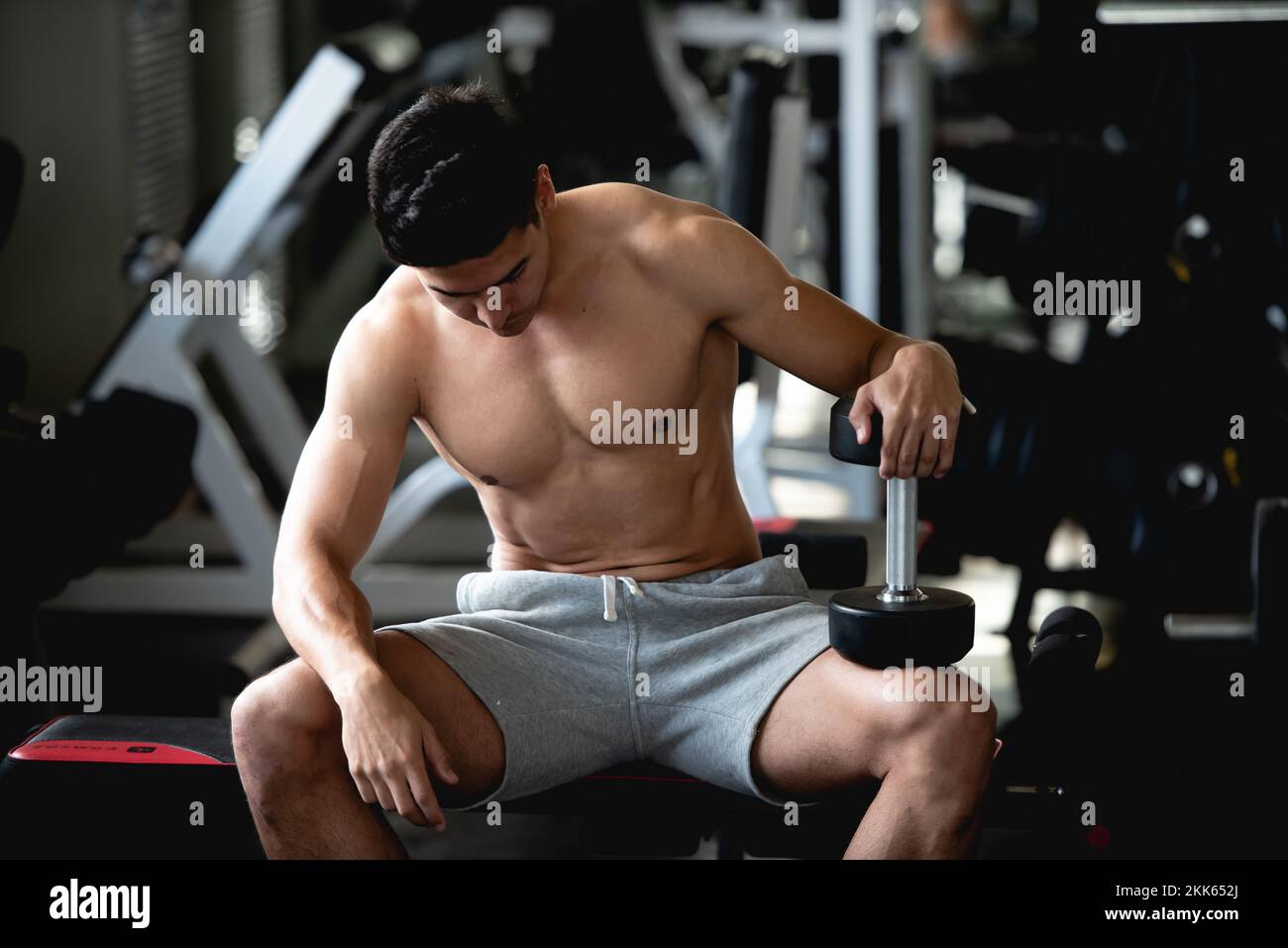 Asian giovane uomo allenamento, sollevamento con manubri per costruire muscoli in palestra. Foto Stock