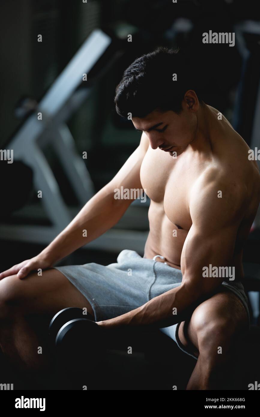 Asian giovane uomo allenamento, sollevamento con manubri per costruire muscoli in palestra. Foto Stock