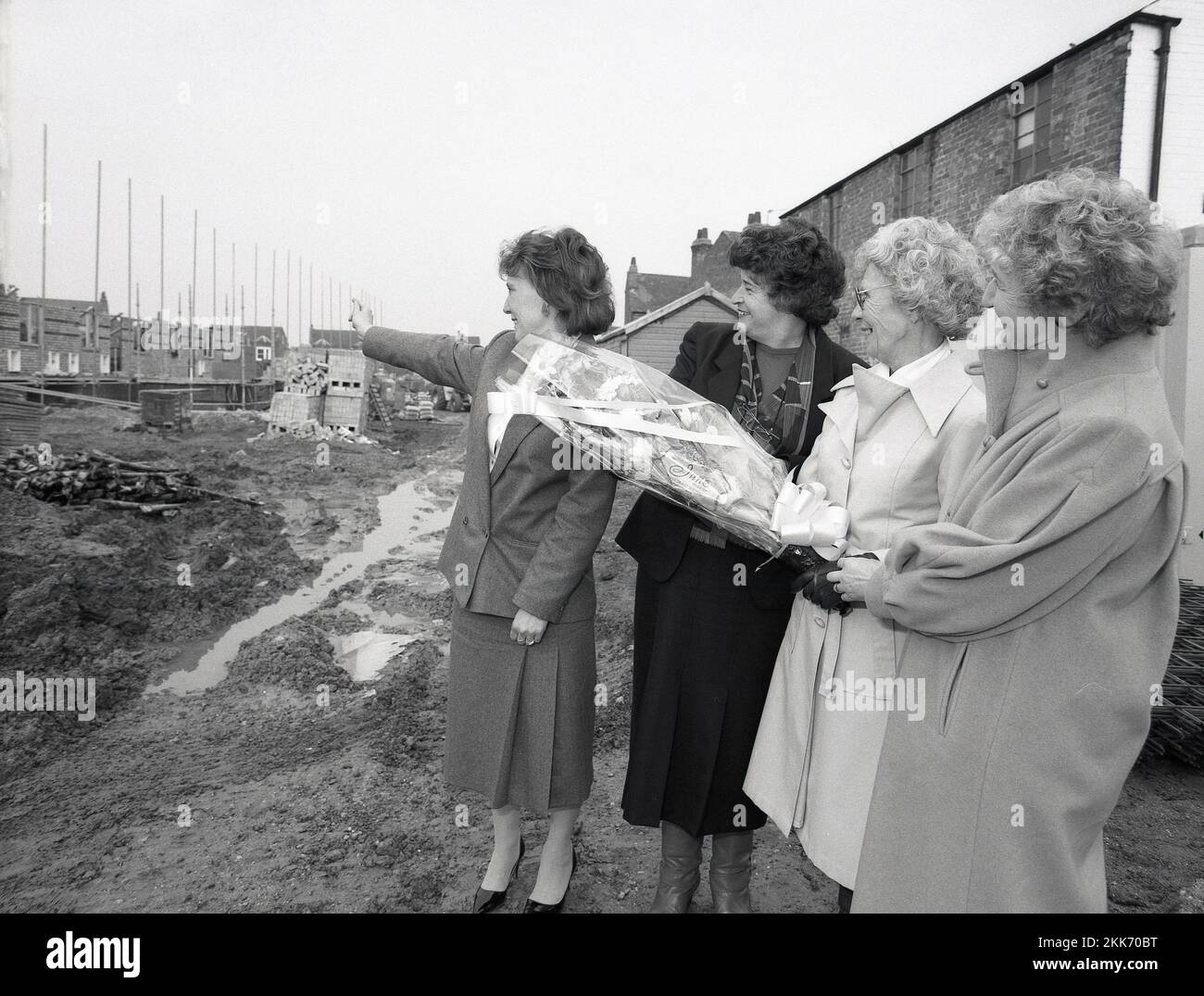 1980s, storico, una donna di vendita che mostra una signora anziana, in possesso di un bouquet di fiori e con i suoi amici, la sua casa è stata costruita su una proprietà immobiliare, Leicestershire, Inghilterra, Regno Unito. Foto Stock