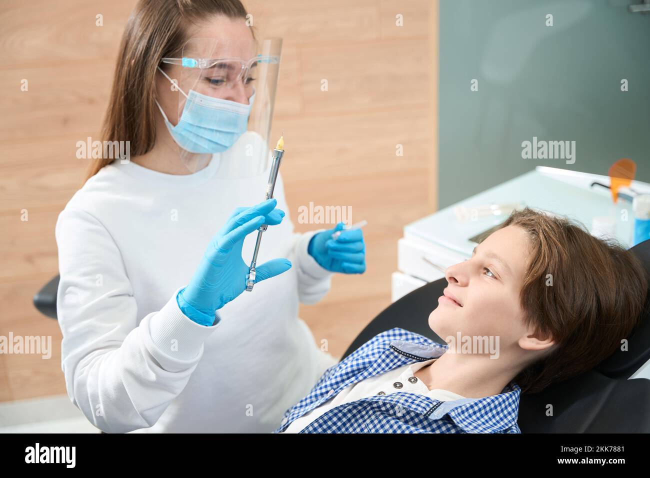 Donna grazioso dentista che tiene siringa con anestesia Foto Stock