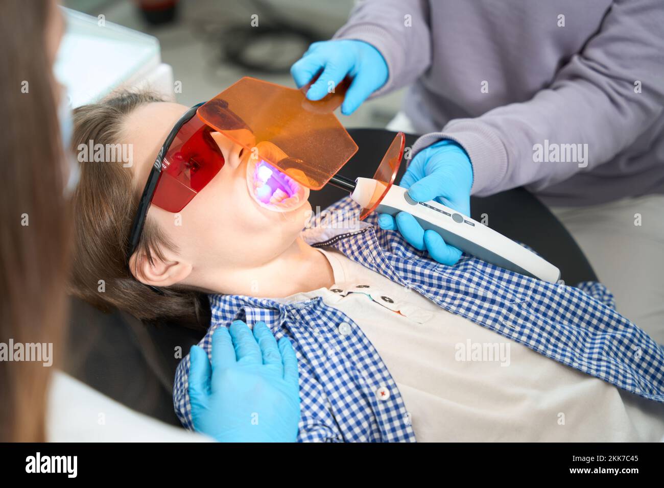Ragazzo in occhiali protettivi si trova in una sedia dentale Foto Stock
