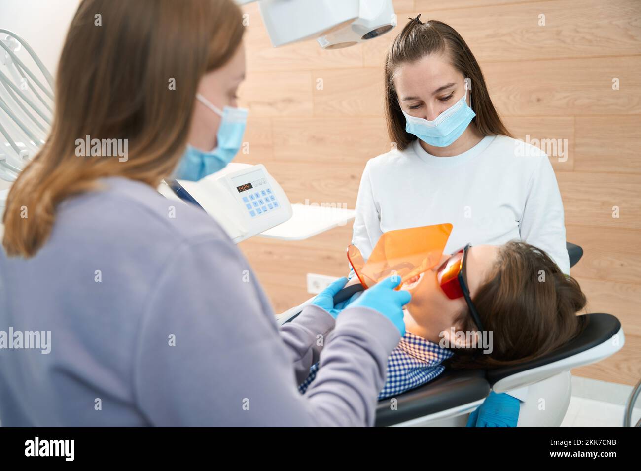 Medico dentista che riempie un dente a ragazzo in studio dentale Foto Stock