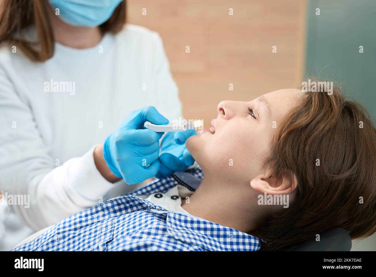 Ragazzo adolescente in clinica dentale ona procedura di selezione del colore del dente Foto Stock